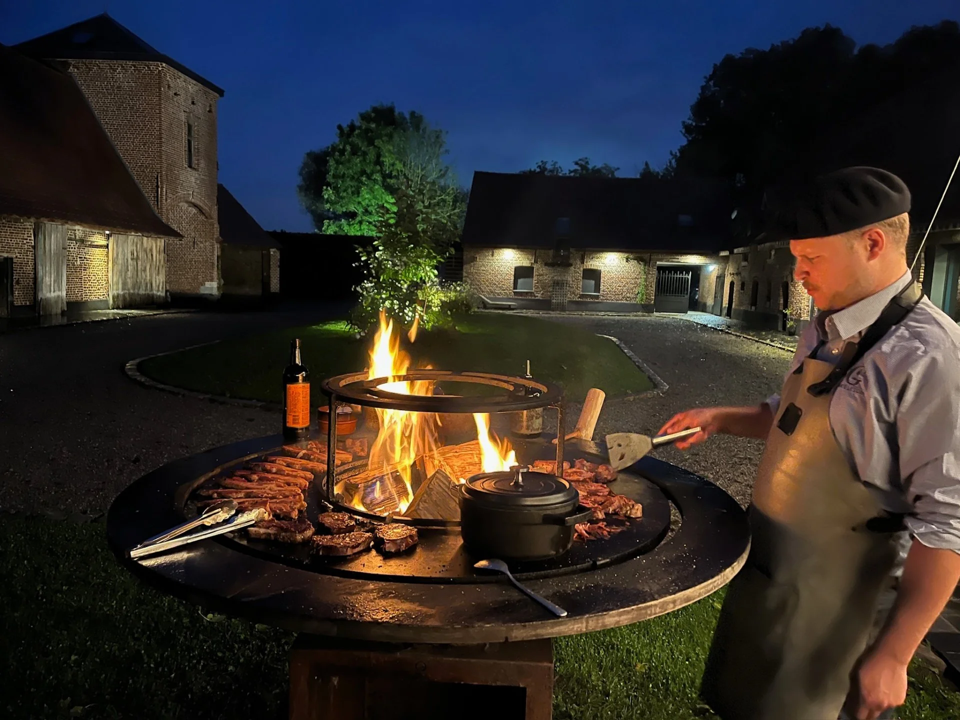 Cuisson au brasero dans la cour de la Cense de la Vigne, à la tombée de la nuit