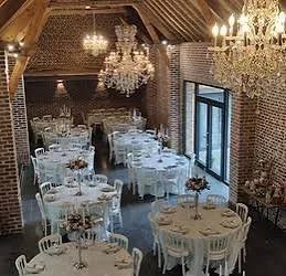 Tables rondes dressées sous les lustres de la Ferme d’Hercule
