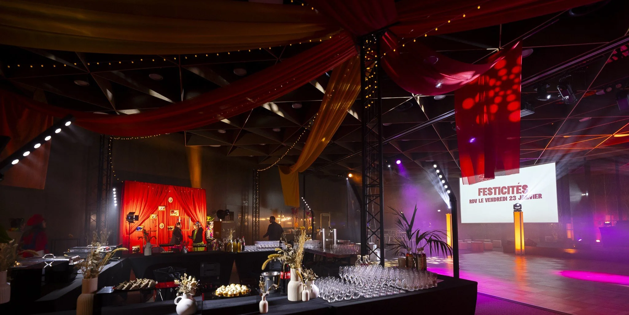 Grande salle de la Cité des Échanges habillée de tentures rouges, buffet dressé pour une soirée d’entreprise
