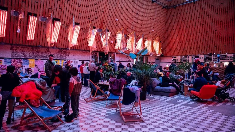 Soirée dans une halle de La Condition Publique, transats et salon sous les lumières rouges