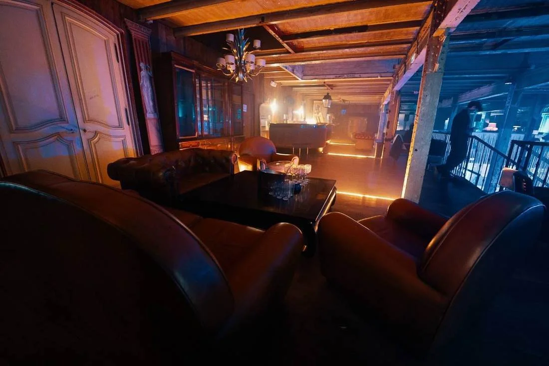 Salon club aux fauteuils en cuir et lumière tamisée, chez Matériaux Authentiques
