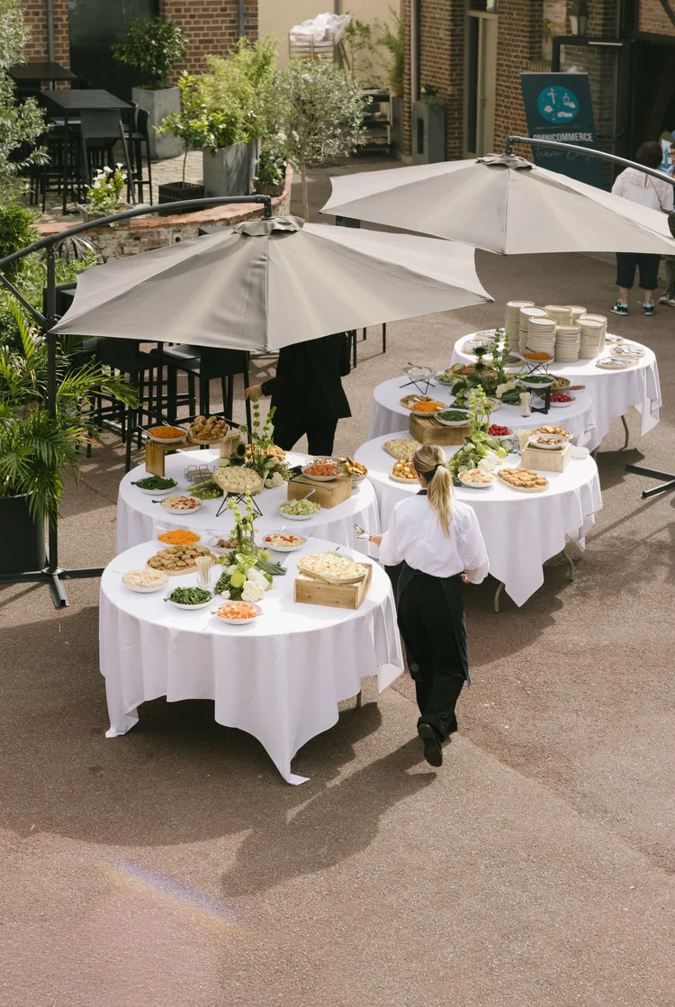 Garden Party : buffet dressé sous des parasols blancs, en plein air
