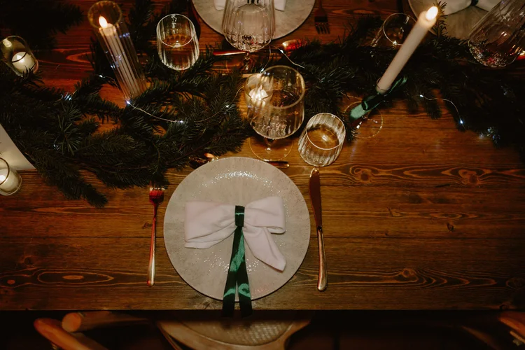 Mariage d'hiver : assiette nouée d'un ruban vert sur une table en bois, bougies et branches de sapin