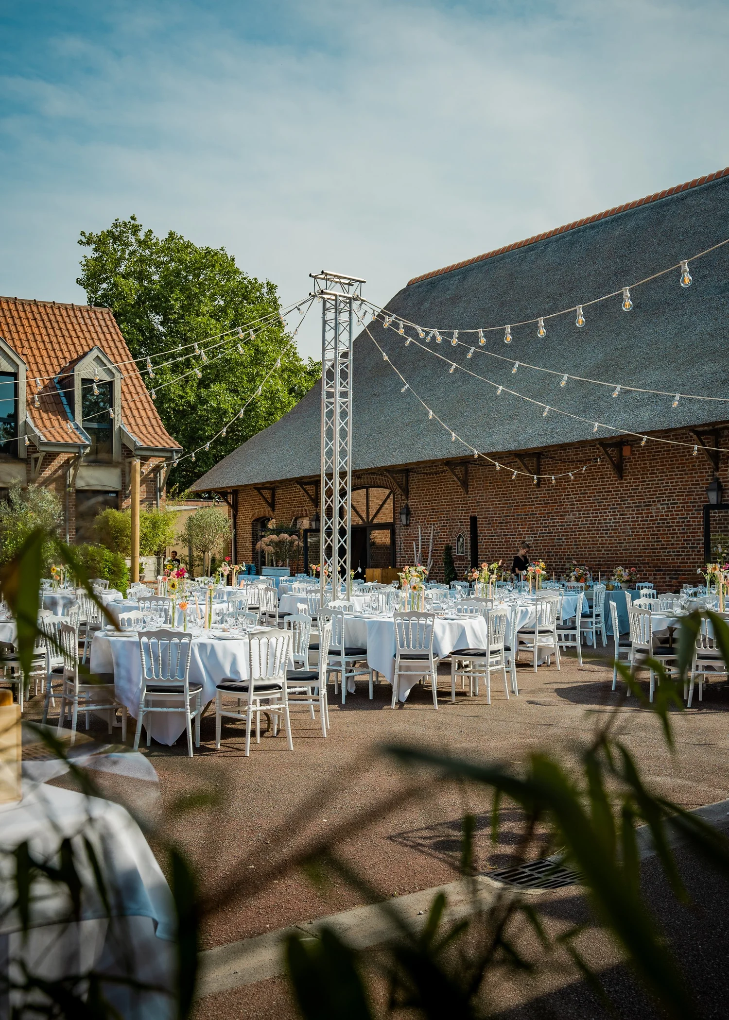 Tables dressées sous les guirlandes lumineuses dans la cour du Clos de la Source