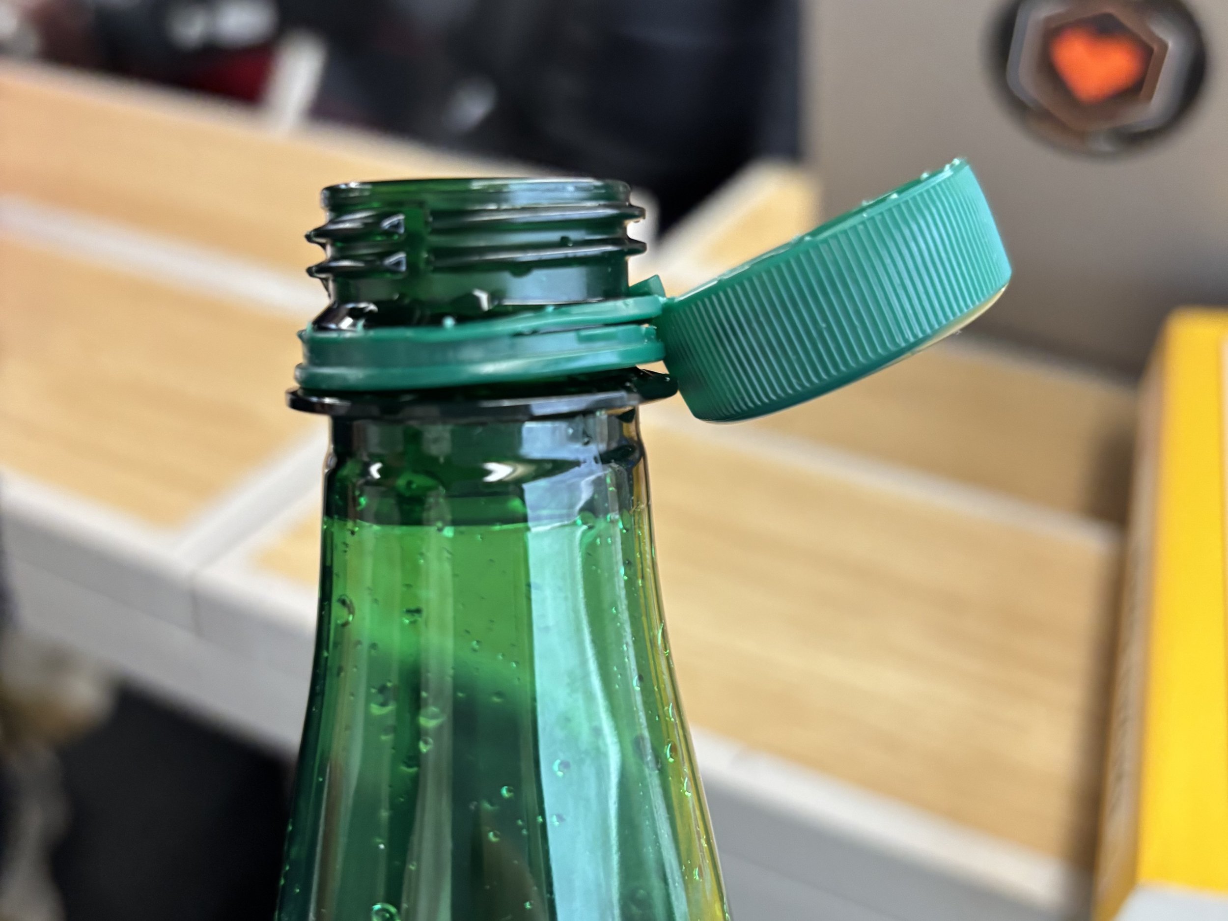 A green plastic bottle with the cap attached, as is typical in European countries