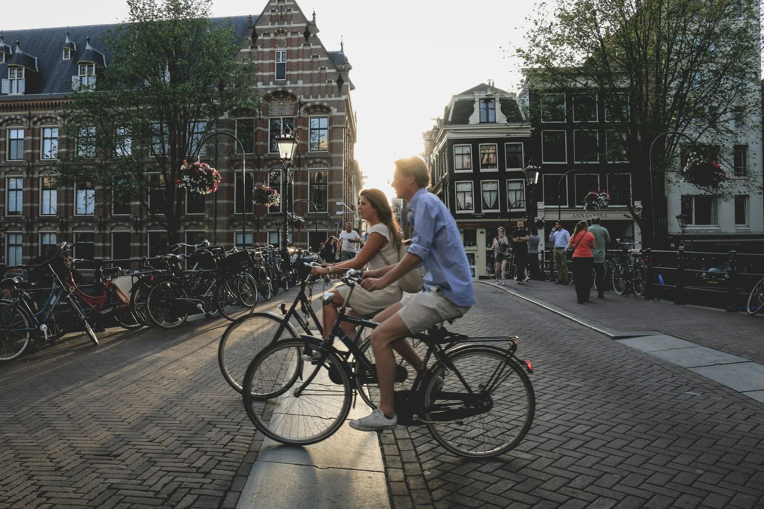 Two adults cycling through Amsterdam, on bricked streets