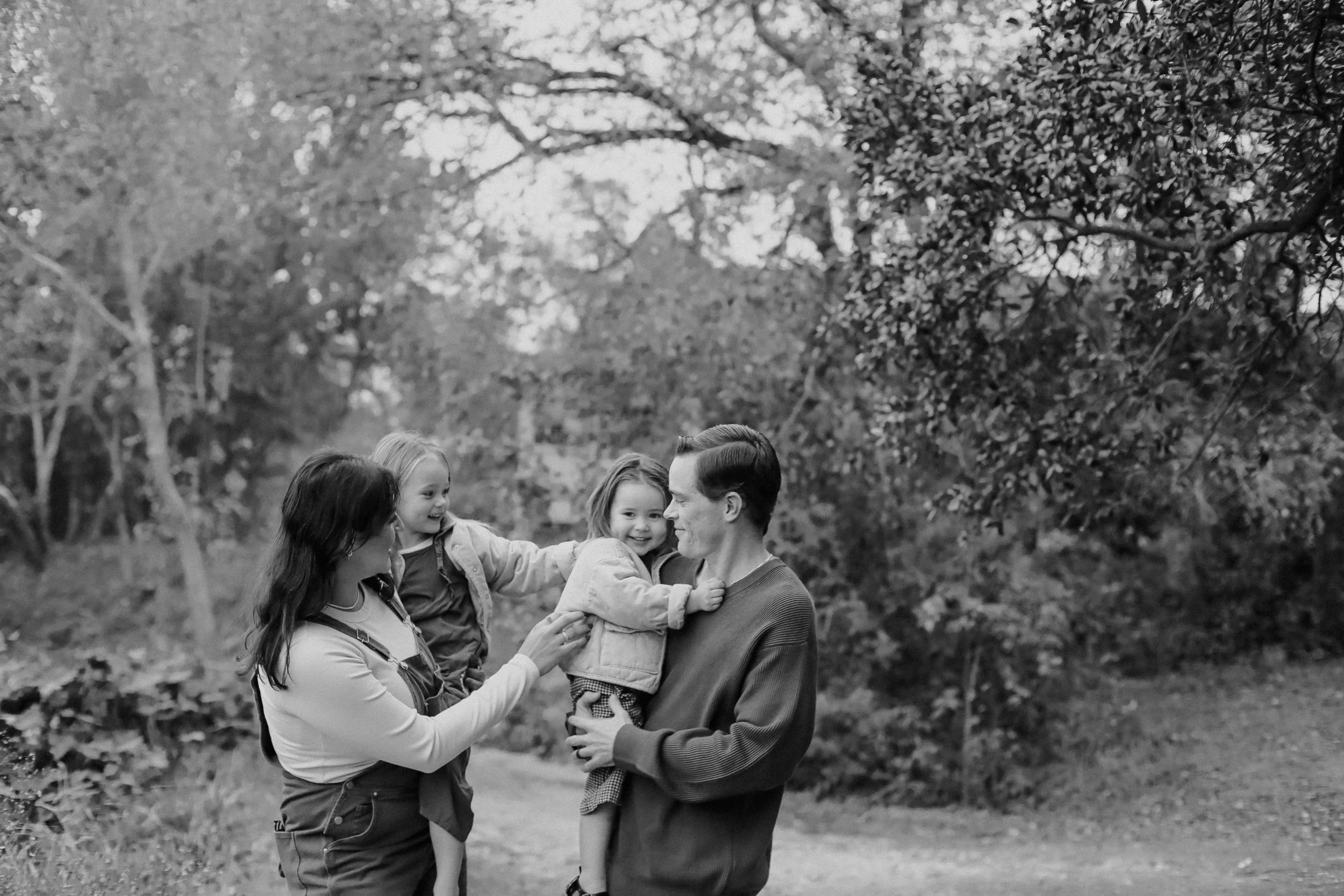 family of four giggles together next to creek by Austin Family Photographer