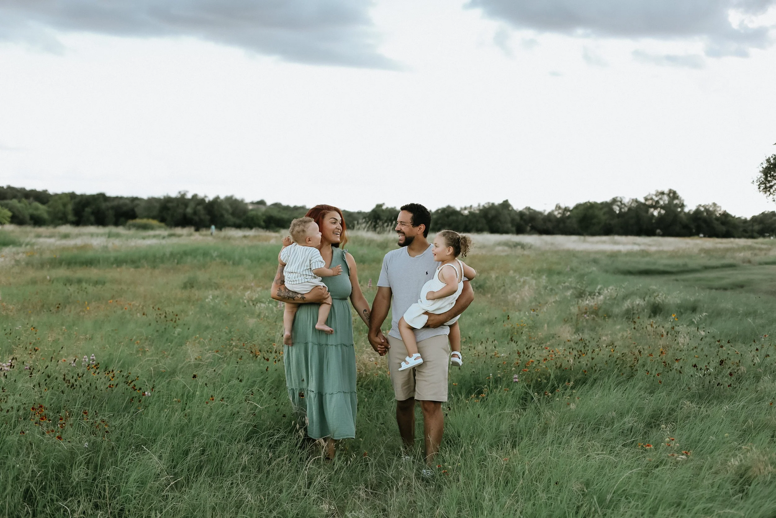 family of four walks in wildflowers by round rock family photographer