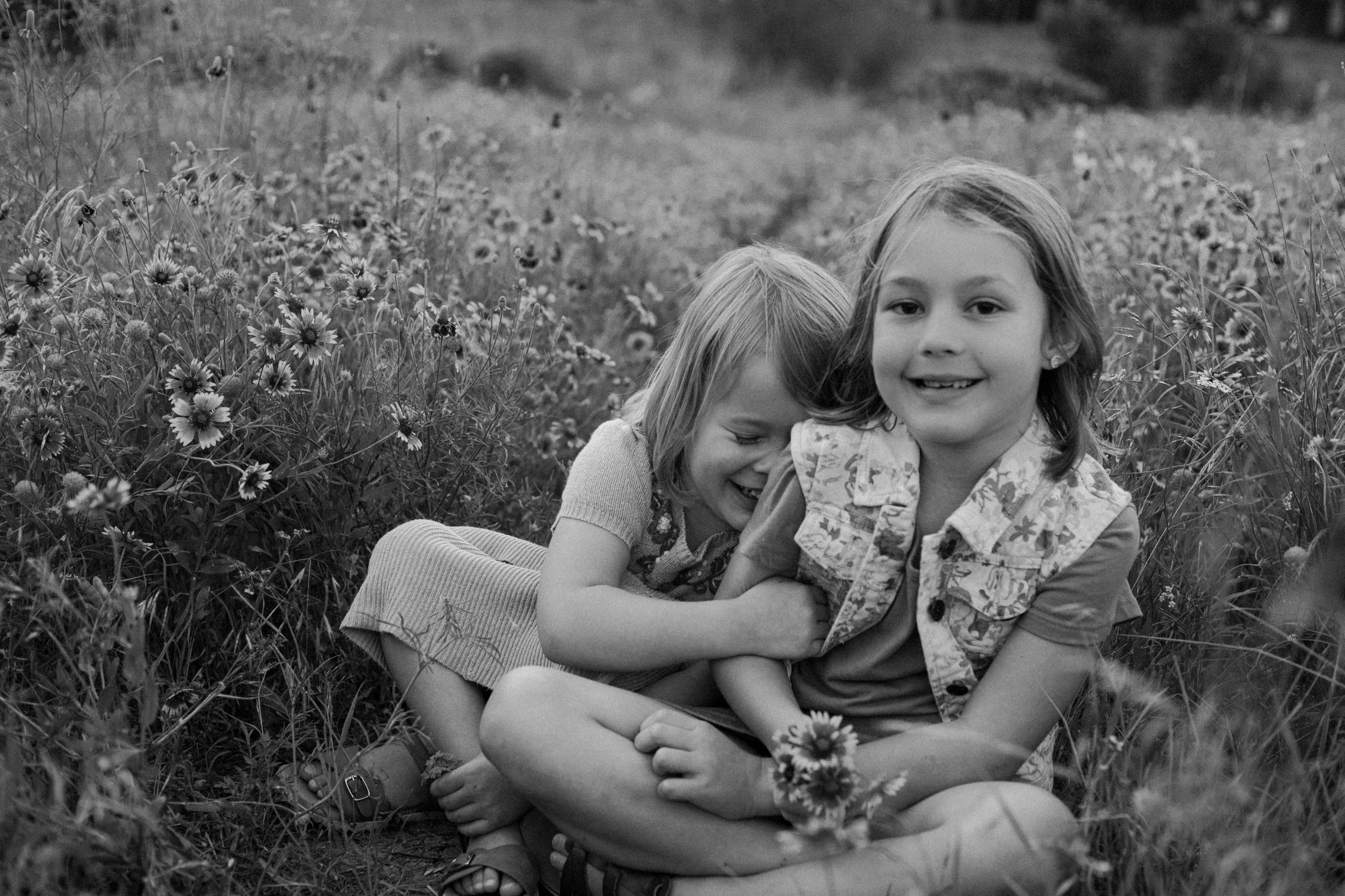 two little girls giggling in wildflower field for mini session