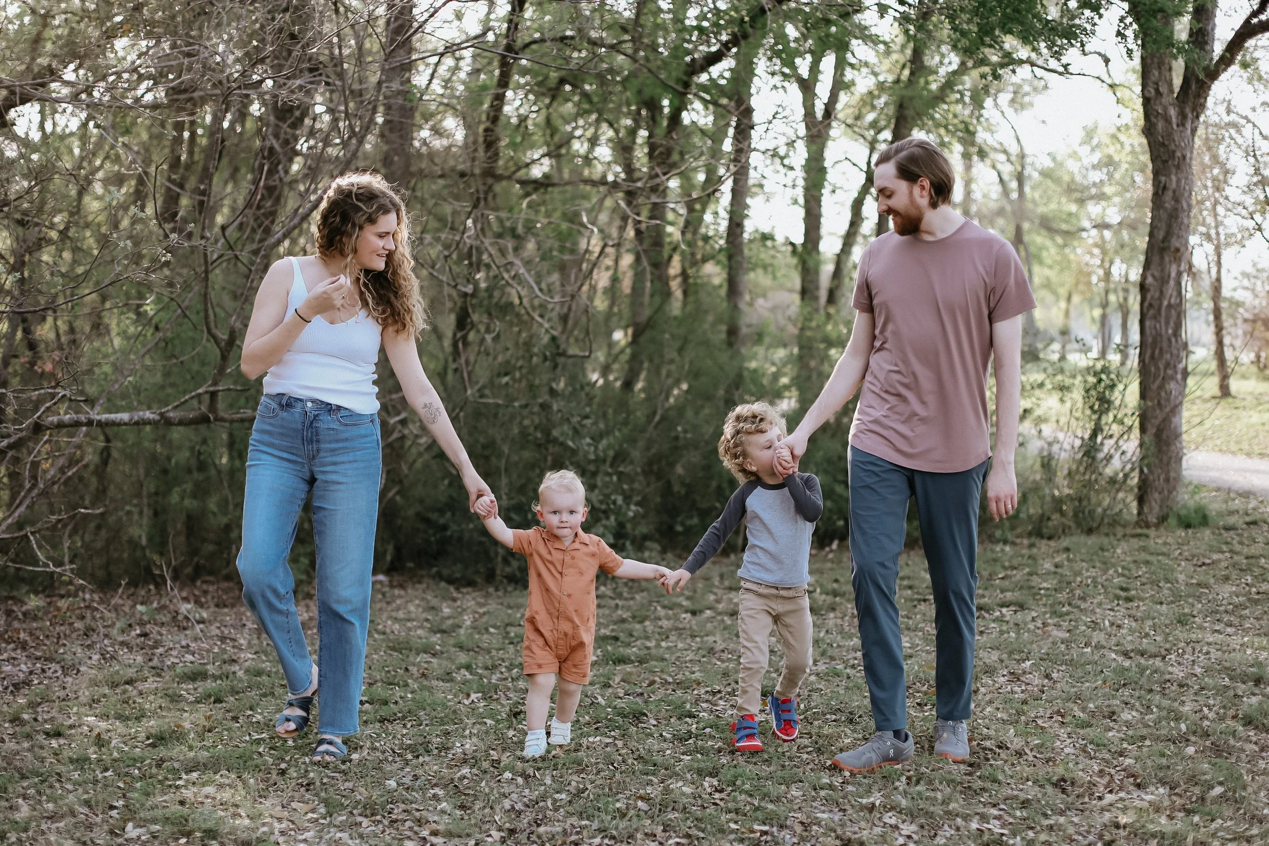 family of four walks under trees by Austin family photographer