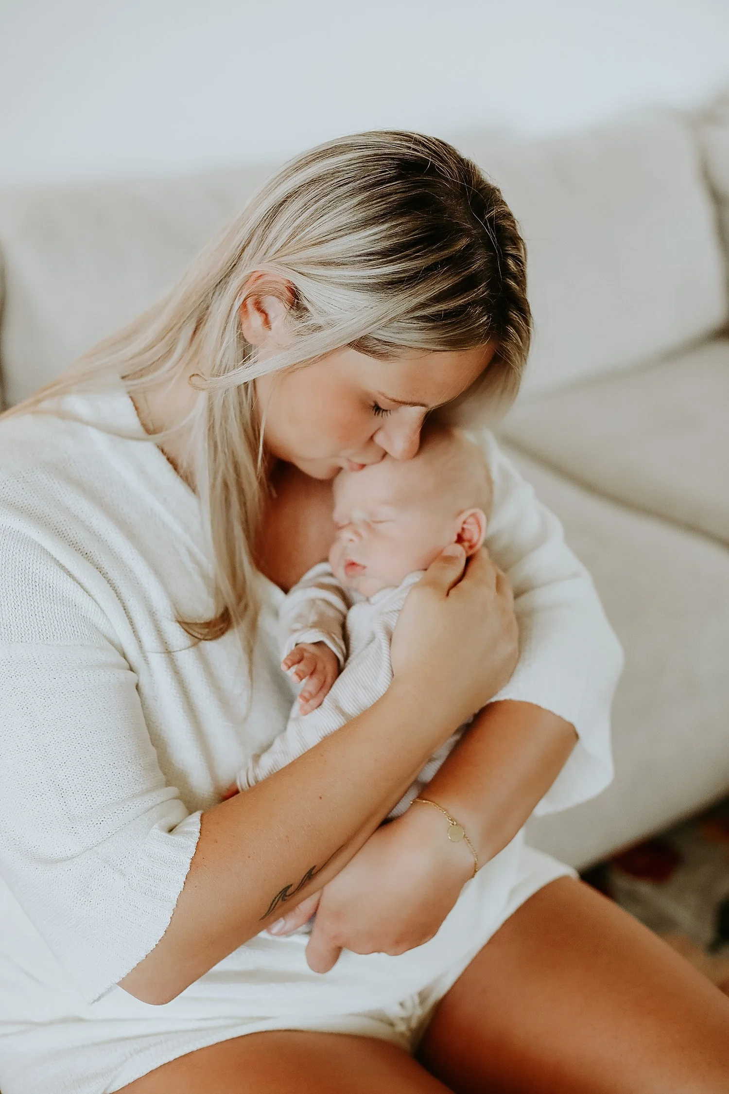 blonde woman holds infant closely by Austin family photographer