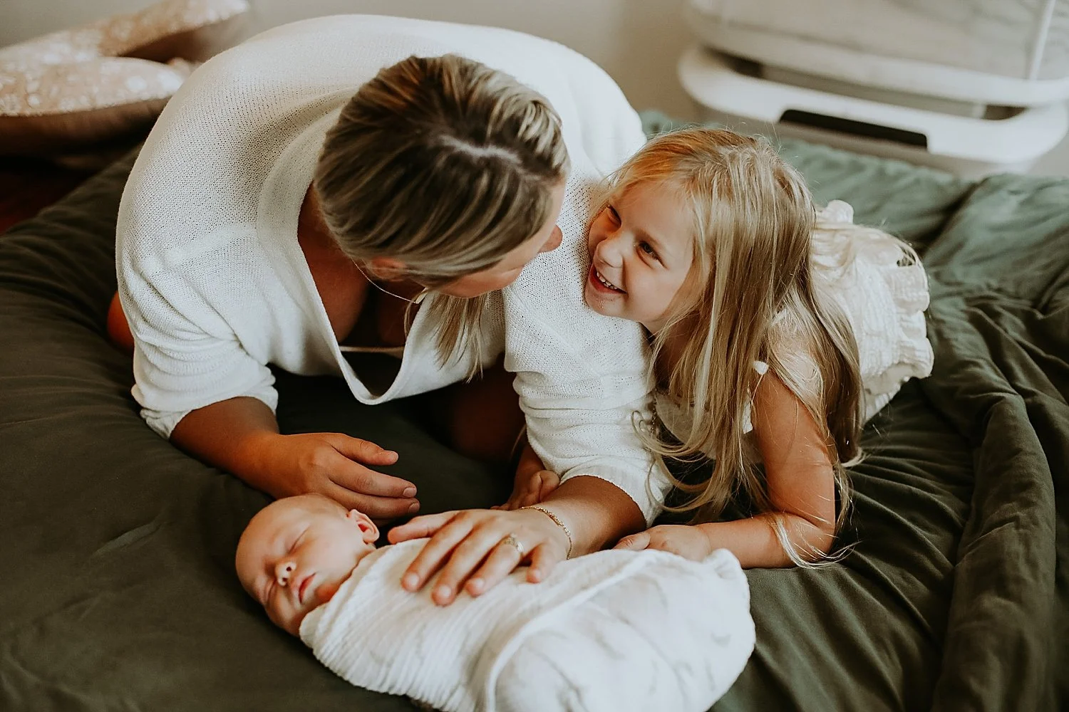 parent and child share a quick smile over baby brother on bed by Austin family photographer
