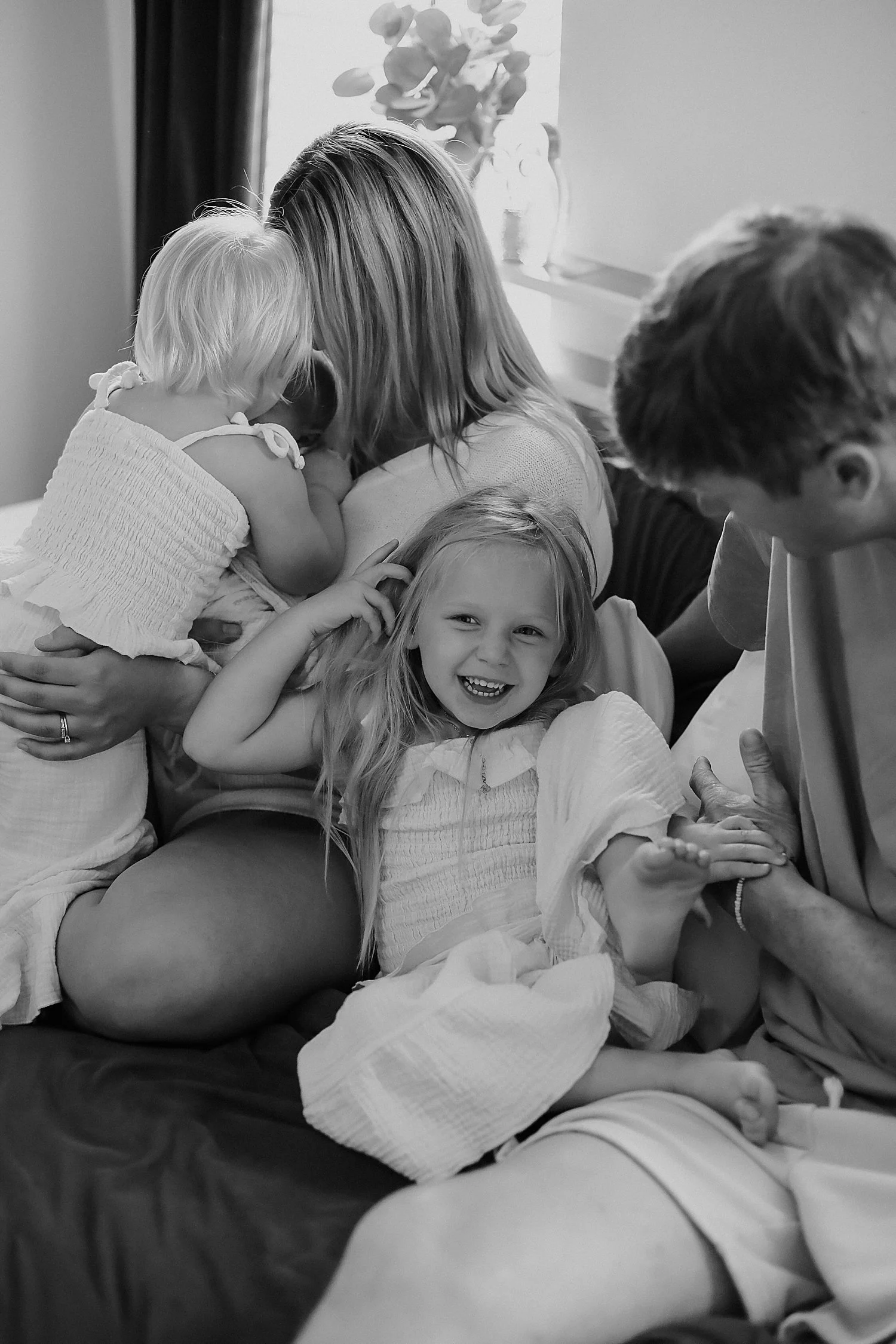 mom and dad snuggle their three little ones on their bed by Jessie Shaw photo