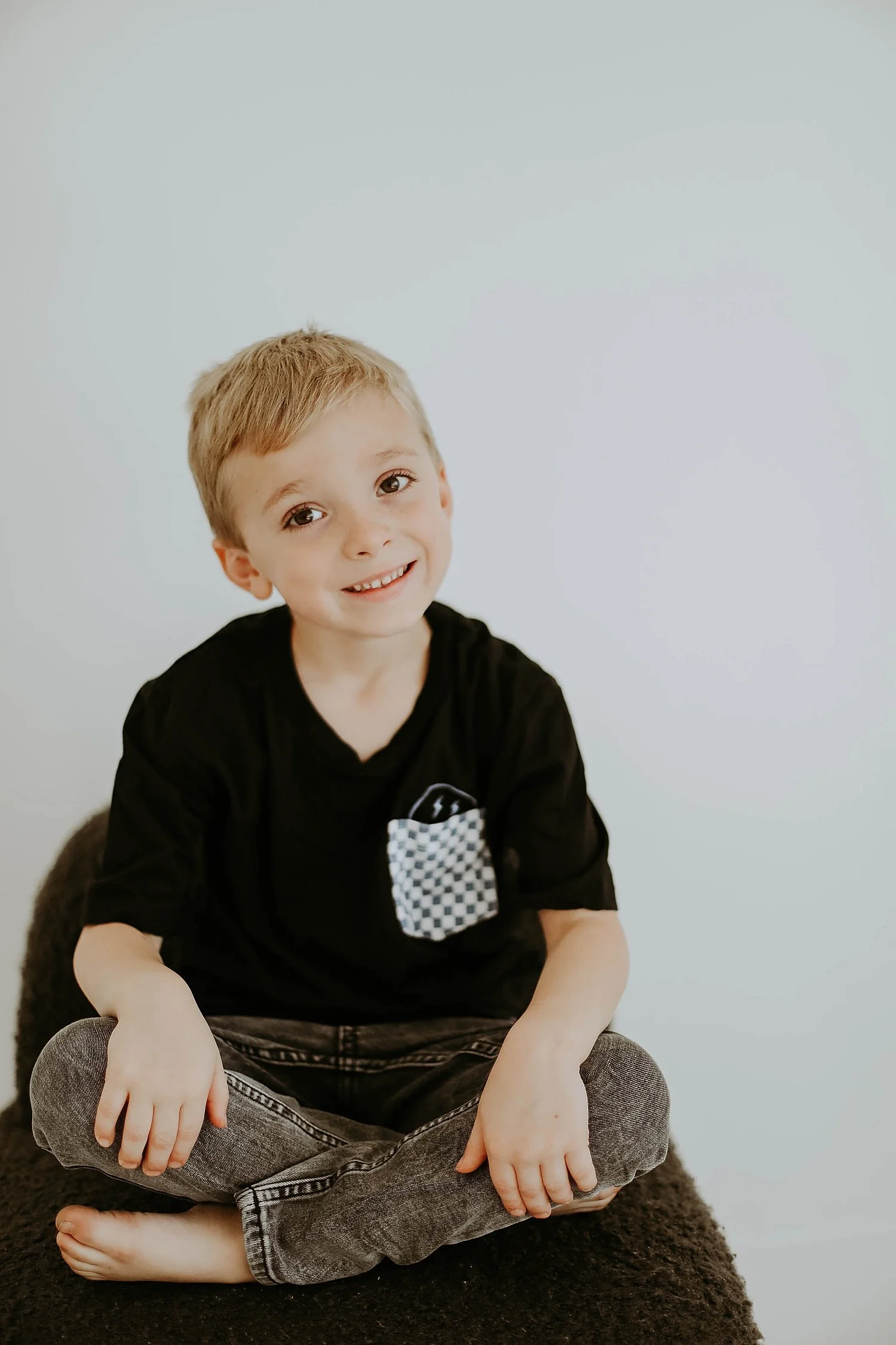  little blonde boy sits on chair in black clothes by Austin family photographer 