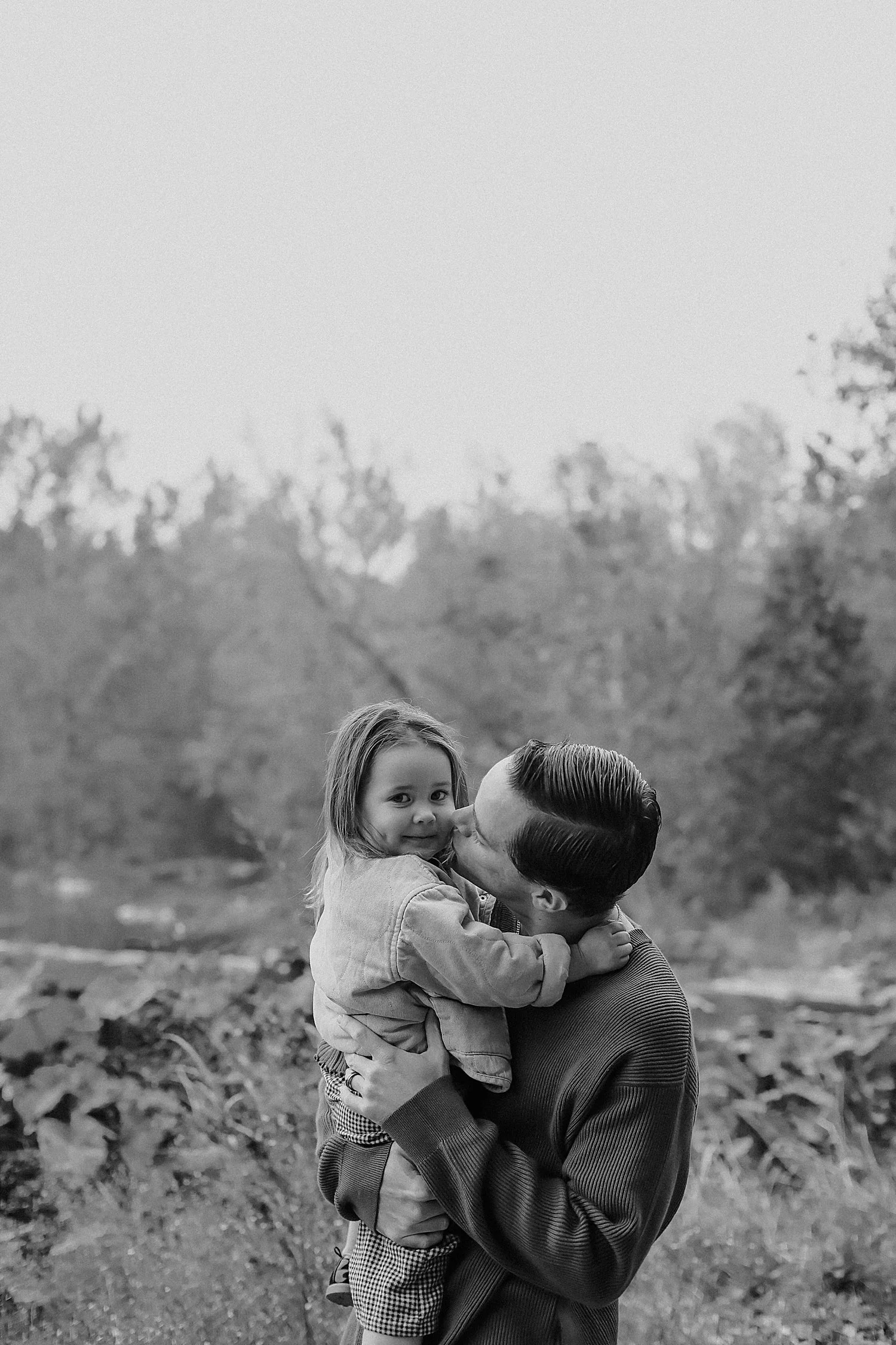  dad holds up small daughter for kiss on cheek by Jessie Shaw Photo 