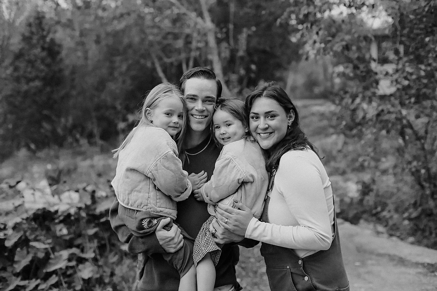  mom and dad snuggle with their toddler daughters for overcast fall session 