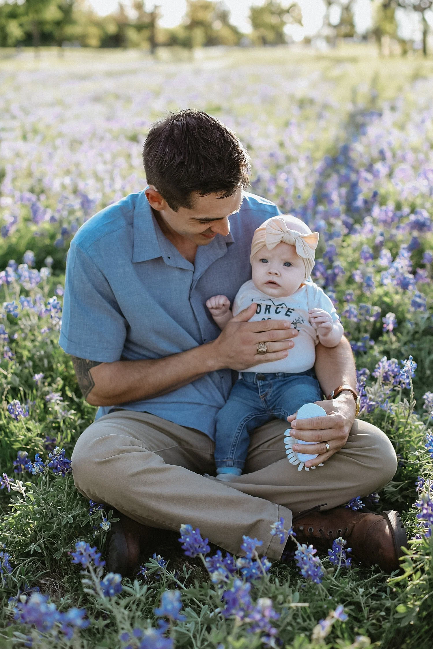  father sits with little one in his lap for Texas Bluebonnet photo session 