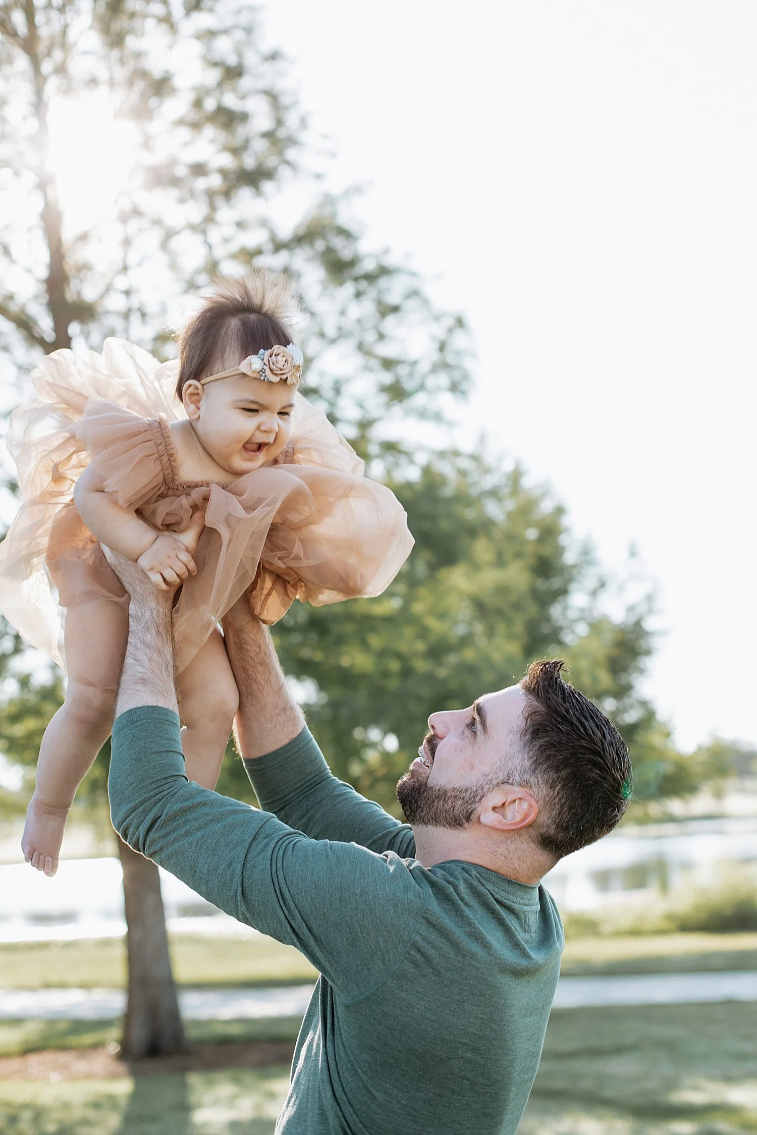  father throws daughter in the air for a playful toss during sunrise milestone session 