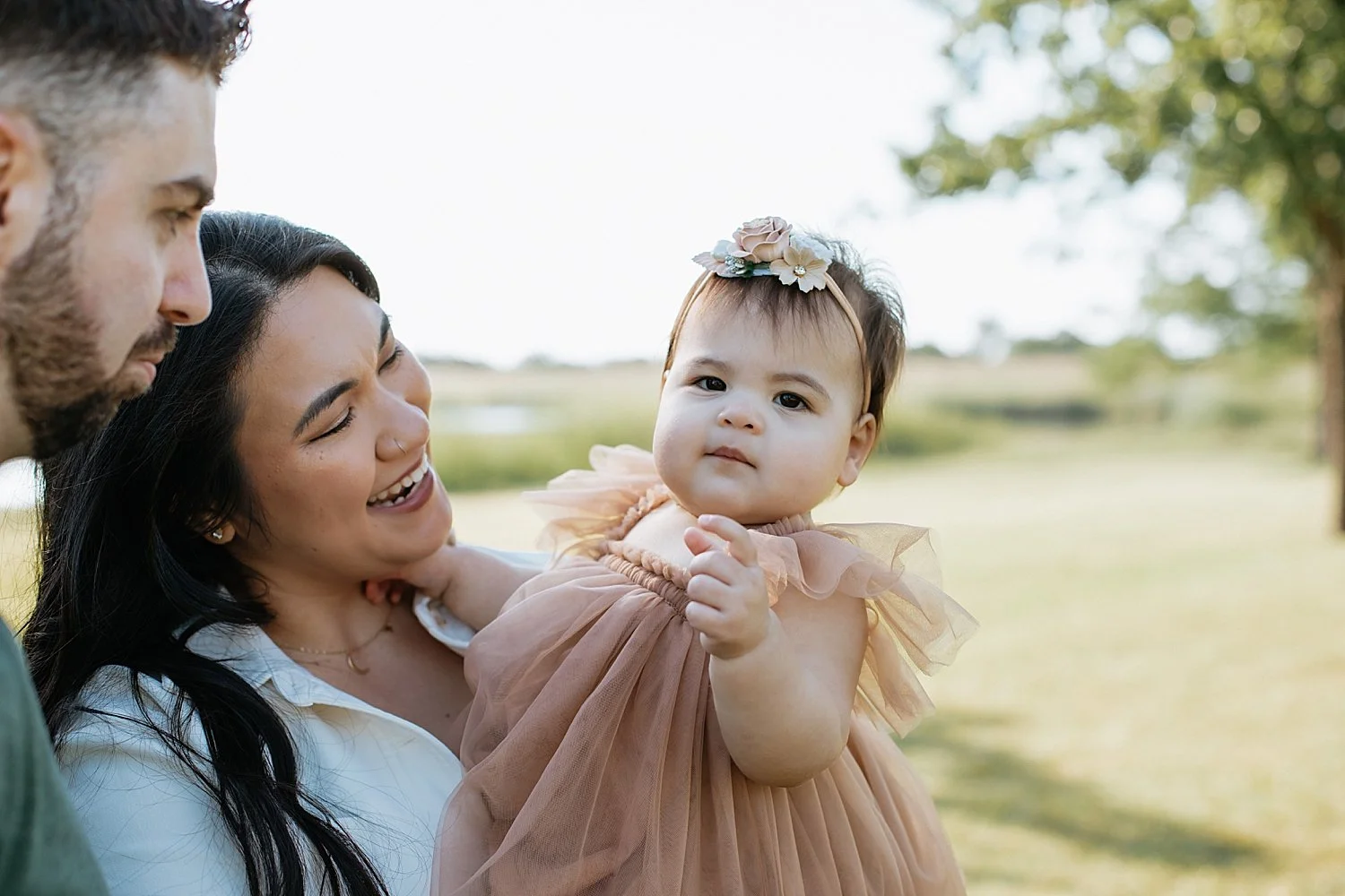  parents hold and gaze at their baby in a tulle dress by Austin Family Photographer 
