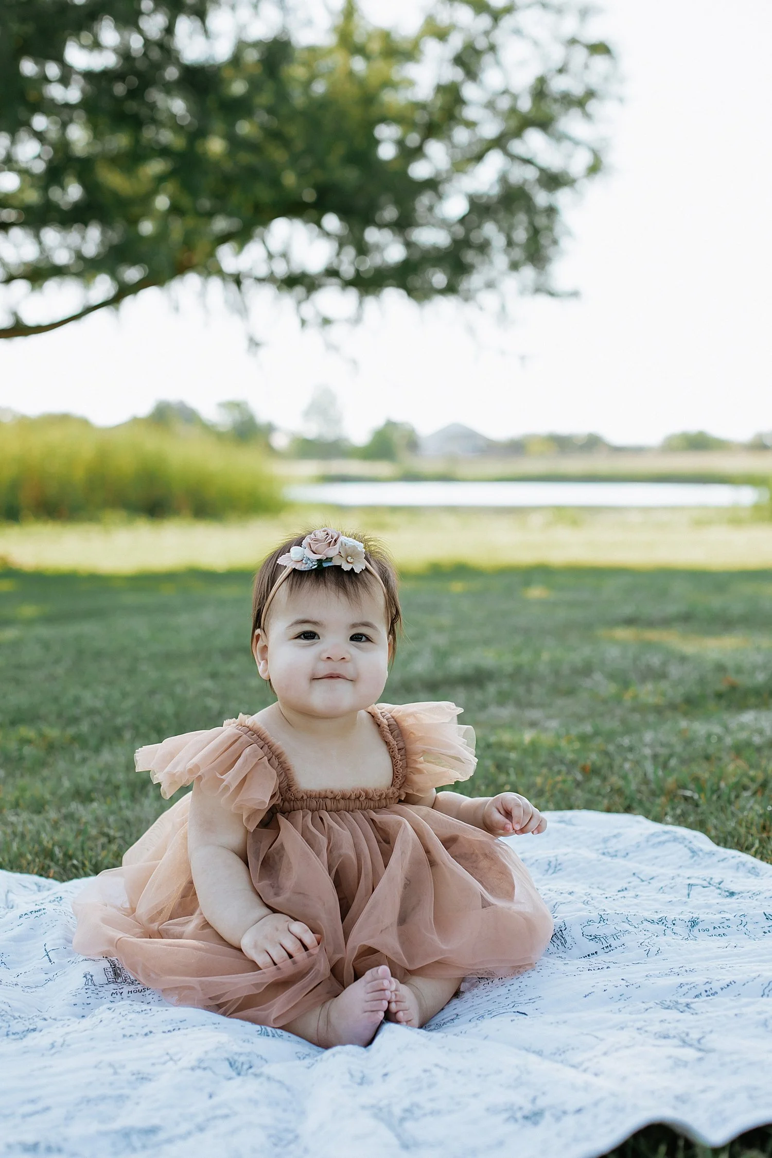  small toddler sits on blanket in the grass by Austin Family Photographer 