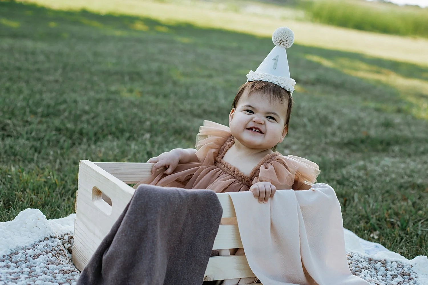  little girl in a birthday hat sits in crate outside by Jessie Shaw Photo 