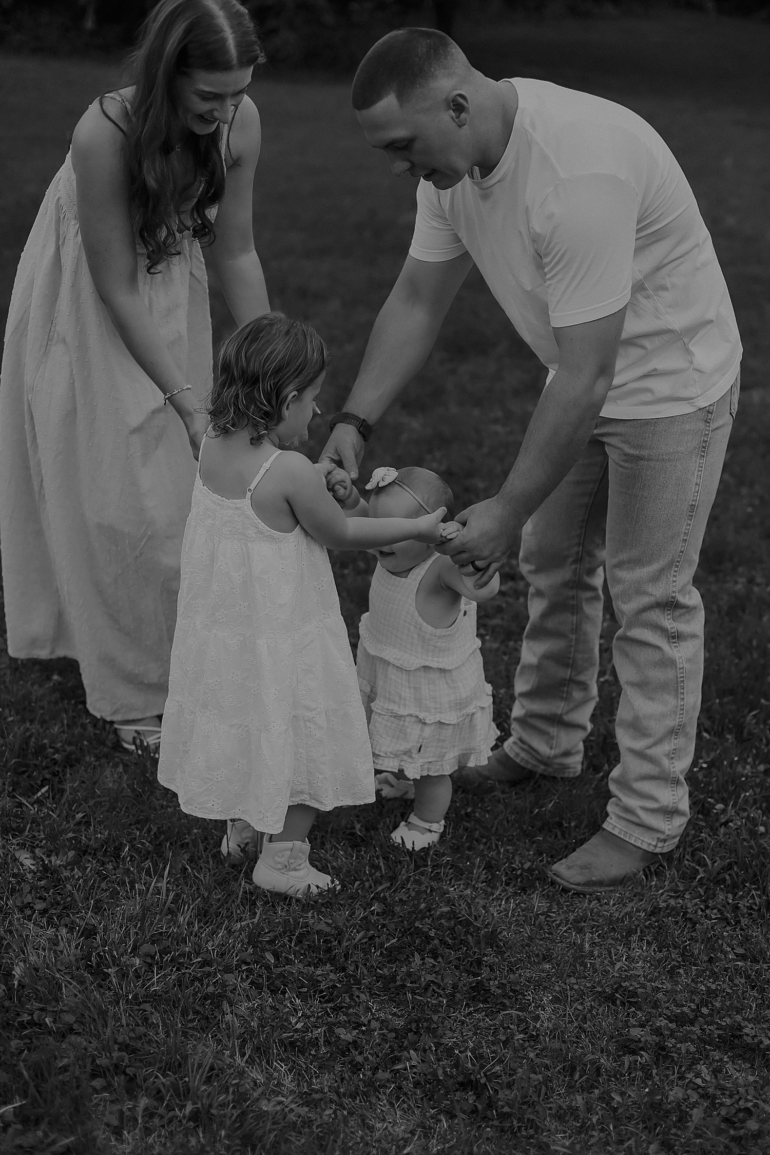  man and woman help their babies as they take steps in grass by Austin and Round Rock photographer 