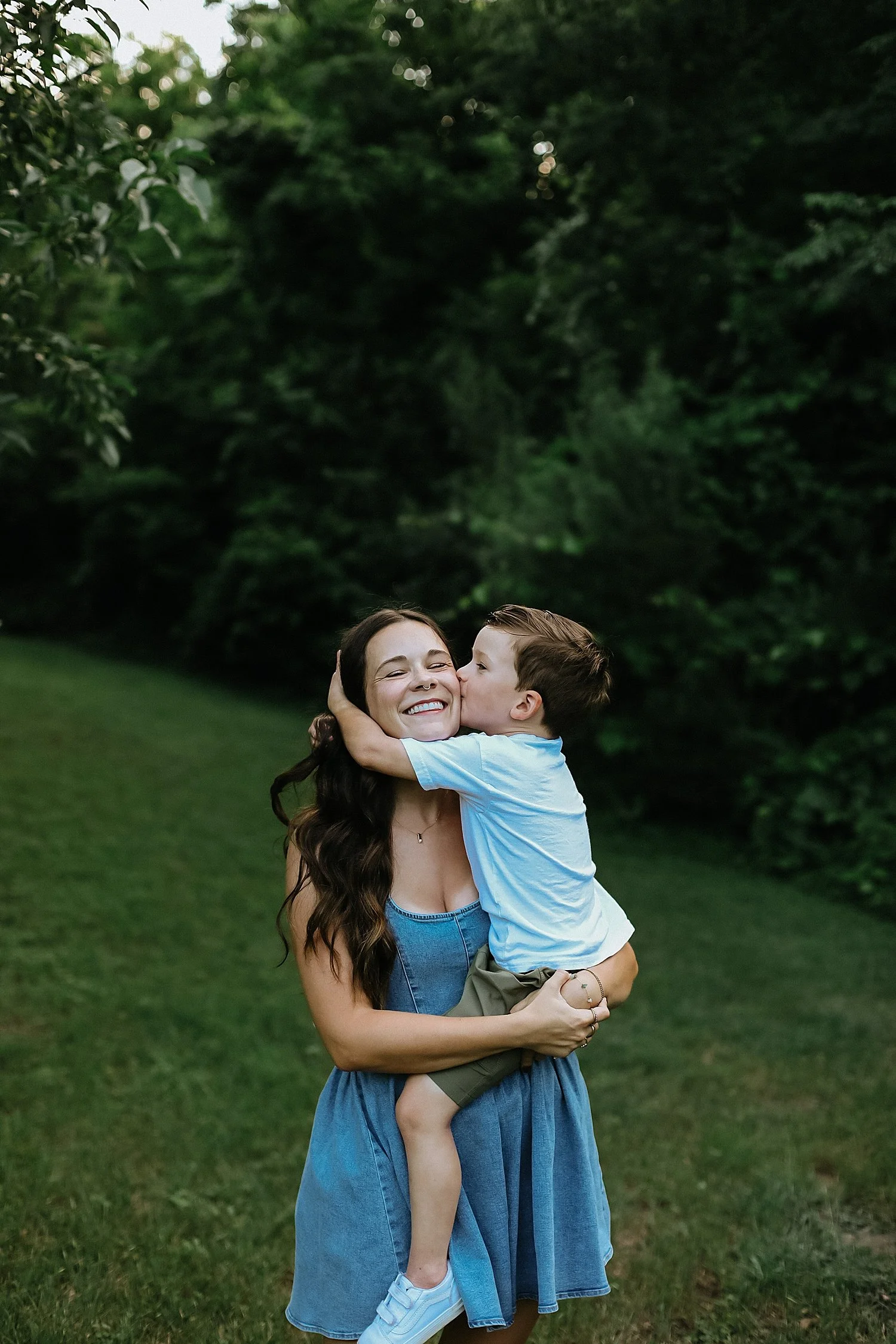  son kisses his mom’s cheek in front of trees by Jessie Shaw Photo 