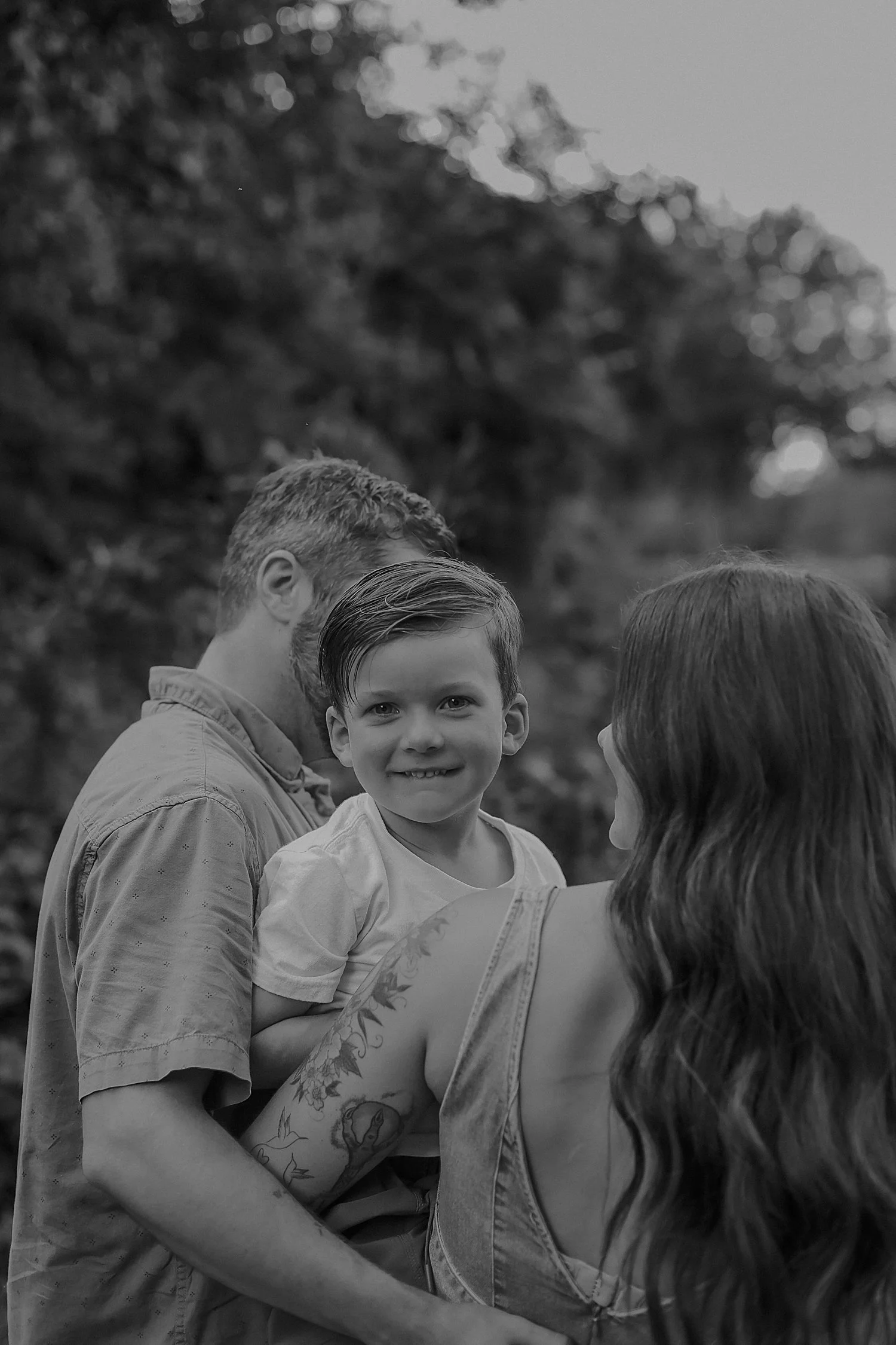  toddler looks over his parent’s shoulders by Jessie Shaw Photo 
