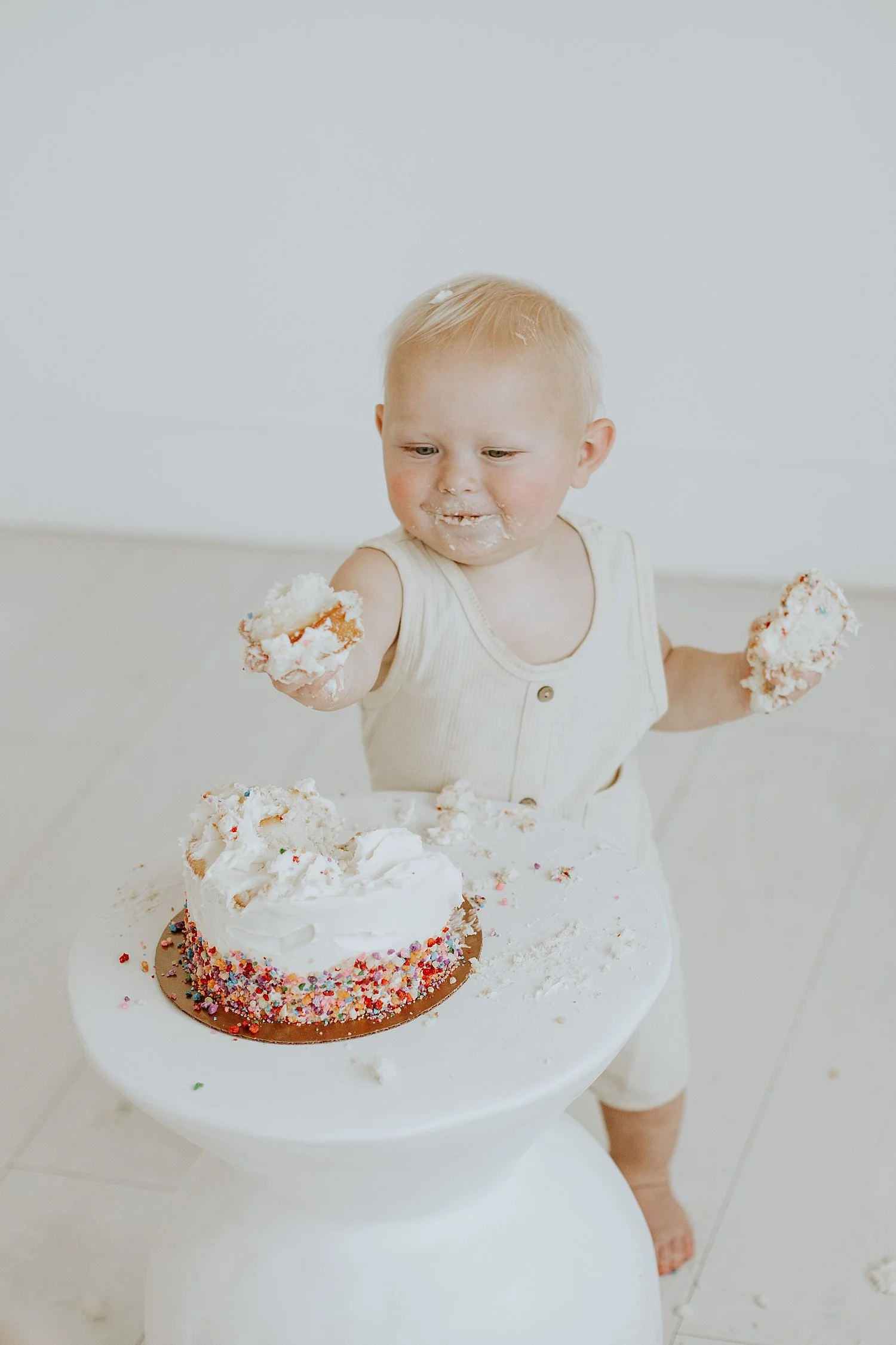  one year old boy shows frosting on finger in white room by Round Rock family photographer 