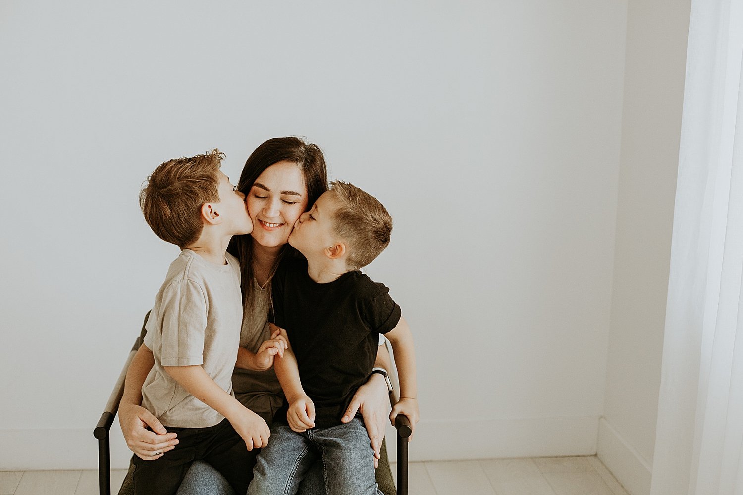  mother holds her boys on chair while they kiss her by Jessie Shaw Photo 