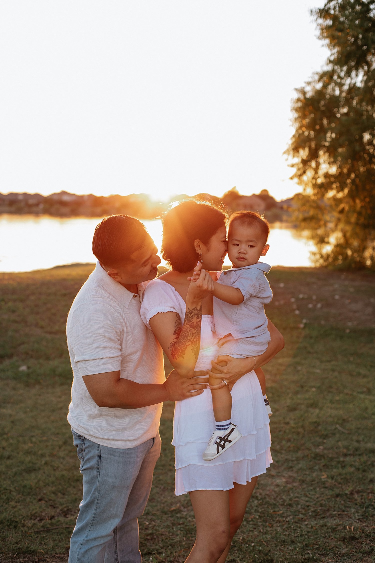  two parents snuggle their one year old by lake by Jessie Shaw Photo 