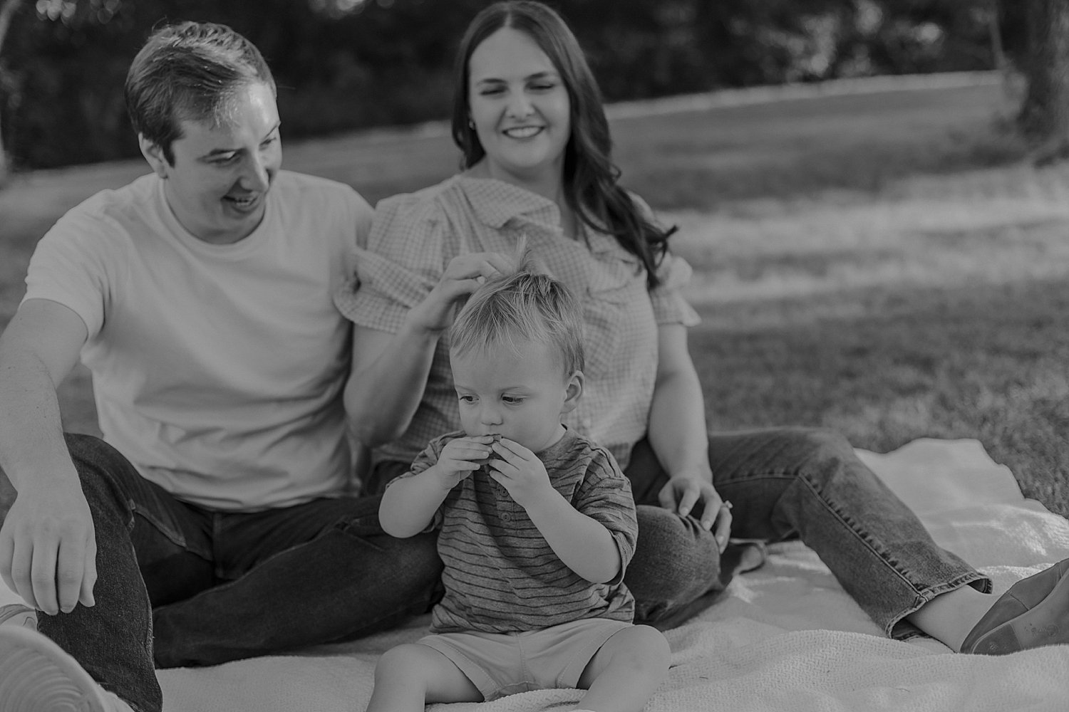  parents snuggle their toddler on blanket outside by Round Rock Family Photographer 