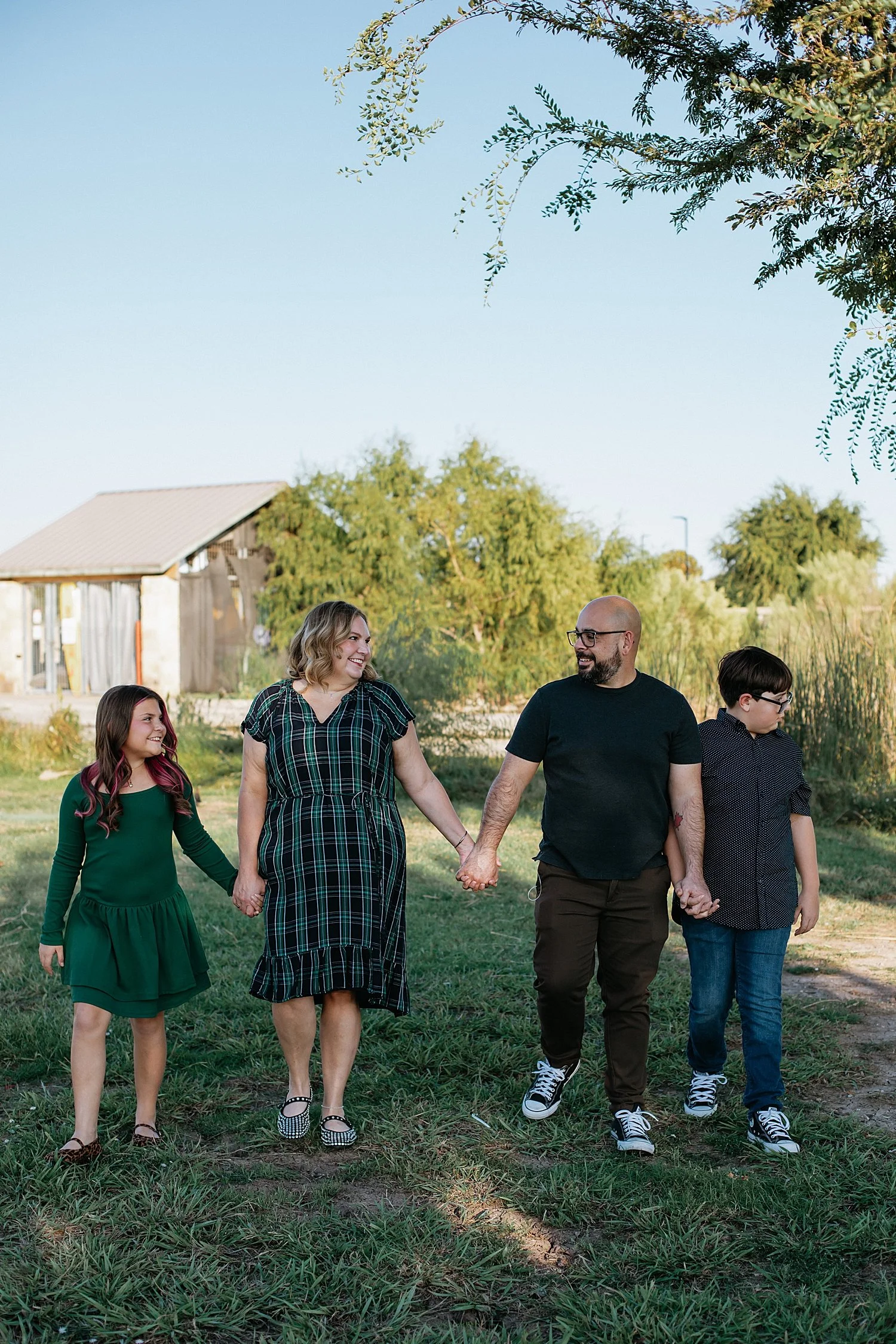  mom and dad walk with middle school children across field for photos at Lake Pflugerville 