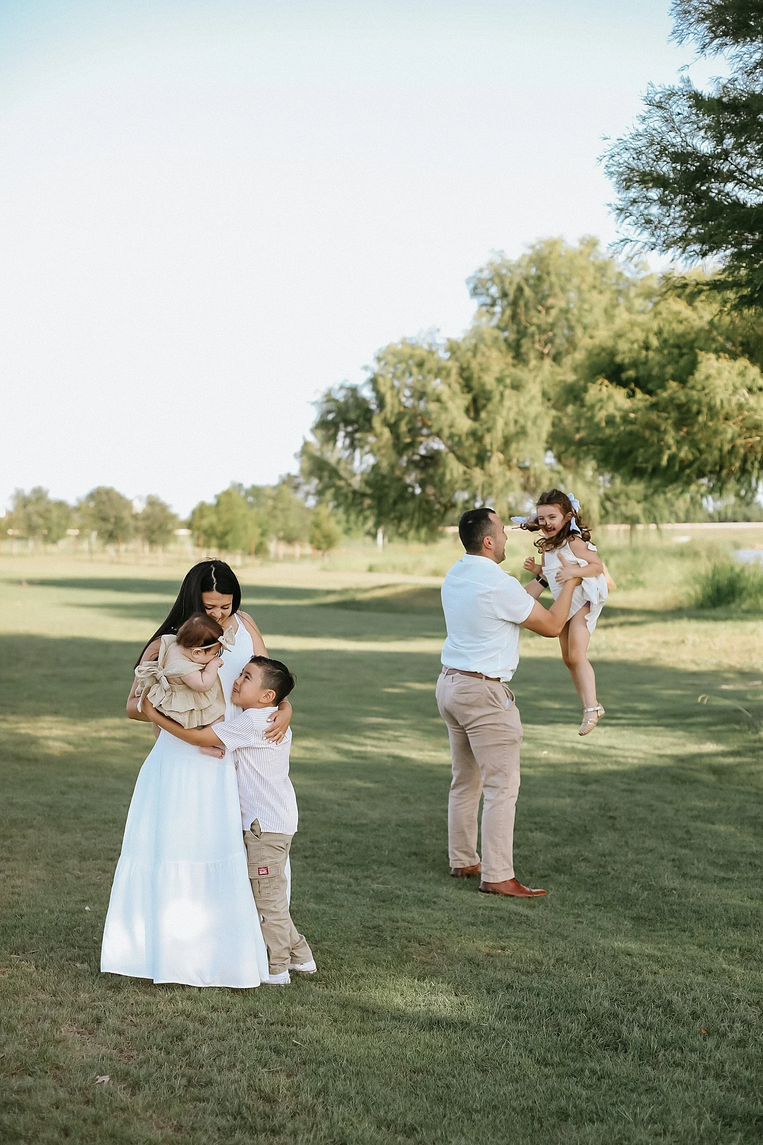  parents play with their kiddos in a field by Round Rock family photographer 