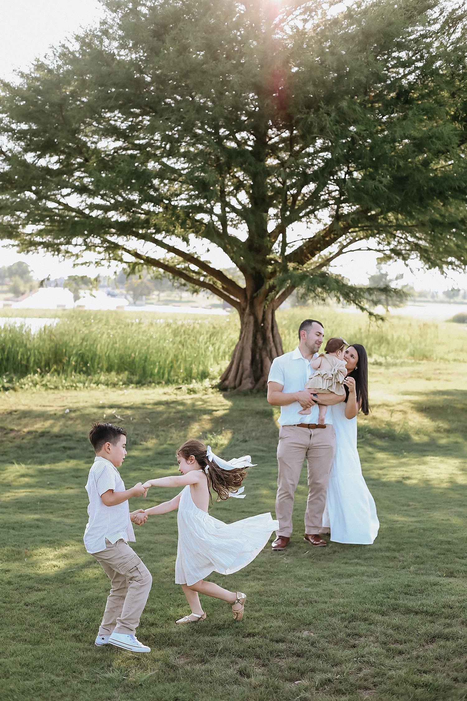  mom and dad watch their kids play under tree for Spring session at Old Settlers Park 