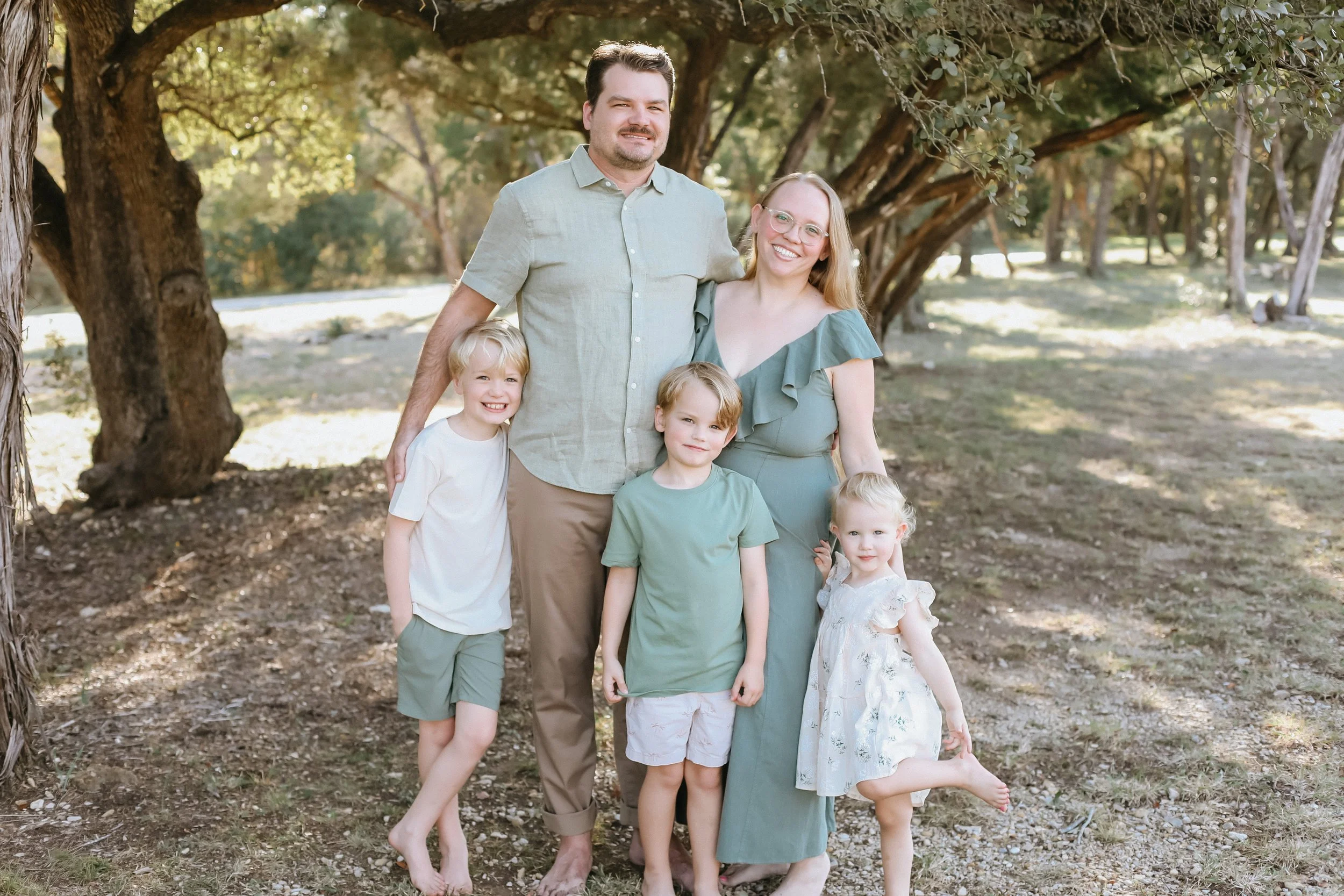 family of five stands in park during golden hour by Austin family photographer