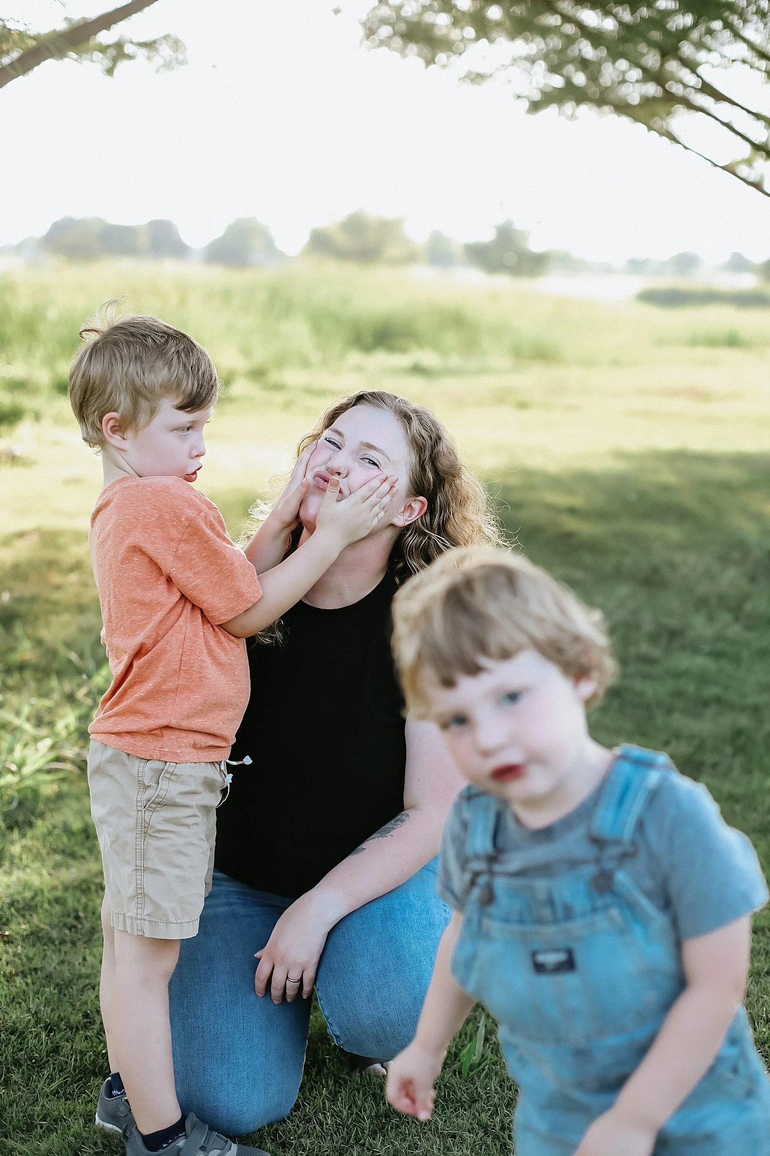 little boy scrunches moms cheeks in play for documentary photography