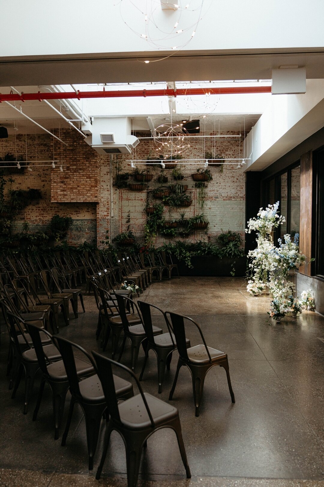 A picture-perfect setting for a wedding ceremony amidst perfectly arranged chairs and exposed brick.