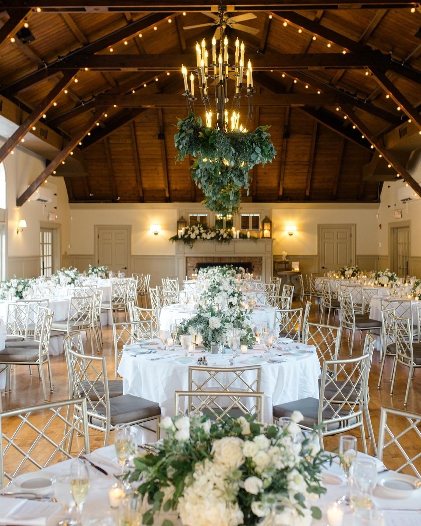 The floral arrangements for Krystina and Ken&rsquo;s wedding were stunning! The eye goes right to the beautiful centerpieces, the mantle behind the sweetheart table draped in flowers, and the chandeliers dangling with flowers and greenery. Truly brea