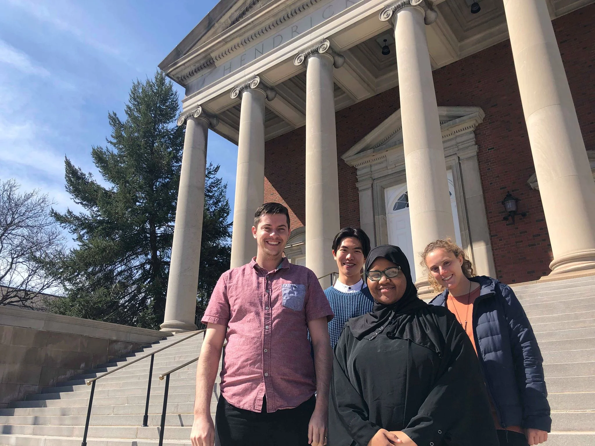Four members of the Student Assembly of Interfaith Leaders, Dallin Evans, Junjie Ren, Dahabo Farah, and Haley Sussman (left to right), stand in front of Hendricks Chapel. Photo Courtesy: Hendricks Chapel