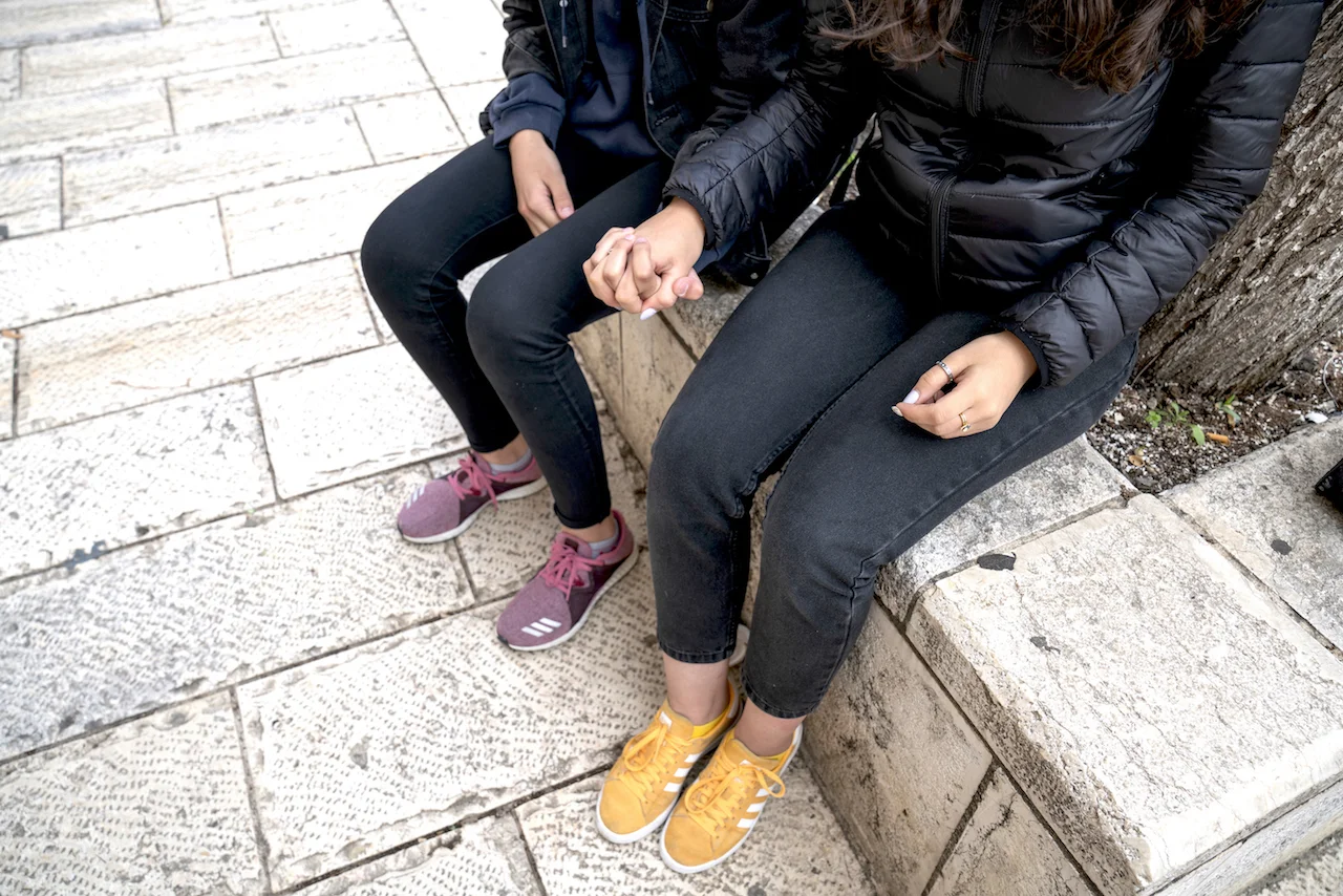 Malak holds hands with her older sister, Shada. They refused to be directly photographed for this story. Photo by Doug Steinman
