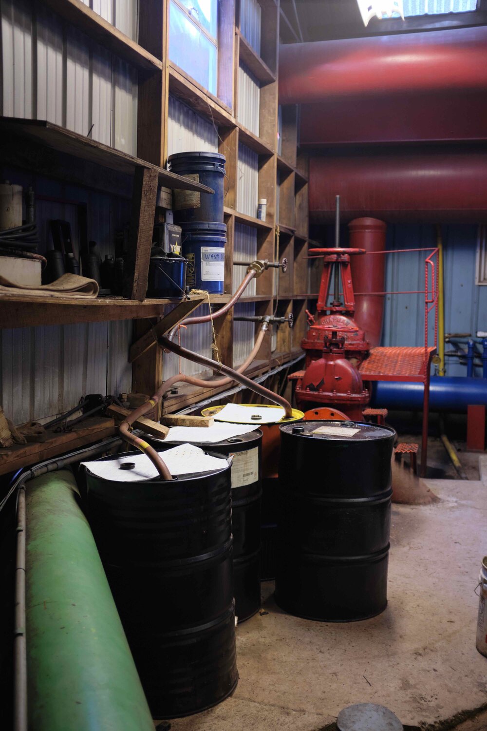  These barrels hold recovered oil from an air/oil separator outside the building. Compressed air comes out of the piston with atomized oil suspended in it. To remove that oil the air is sent through a vortex and recovered for reuse.  