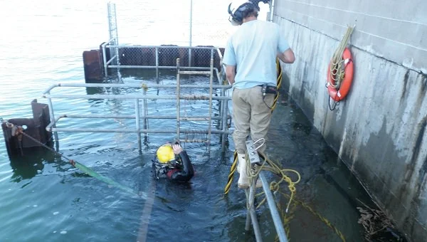Diver and tender working preparing to burn old guide for removal