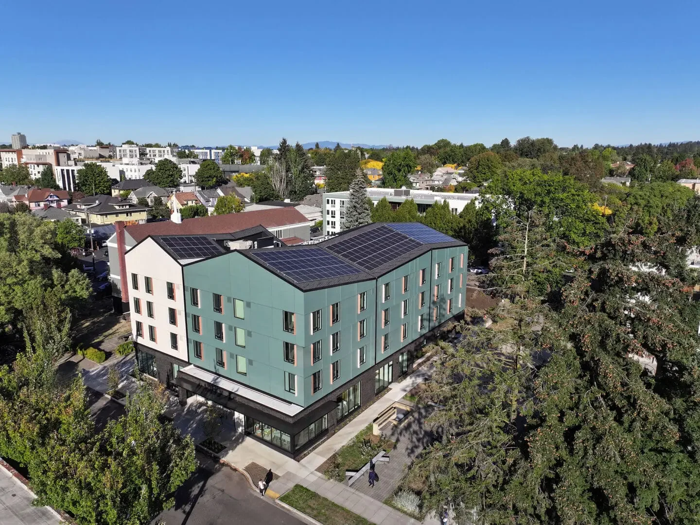 An aerial view of Francis + Clare Place, a four story green and white apartment building.