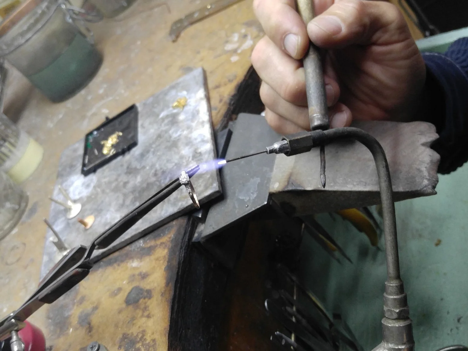 Close-up of a person repairing a diamond ring in a jewelry workshop.