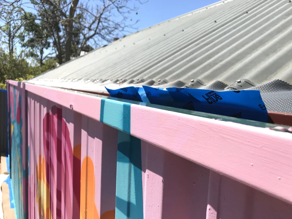 removing tape from a mural on colorbond fence.jpg