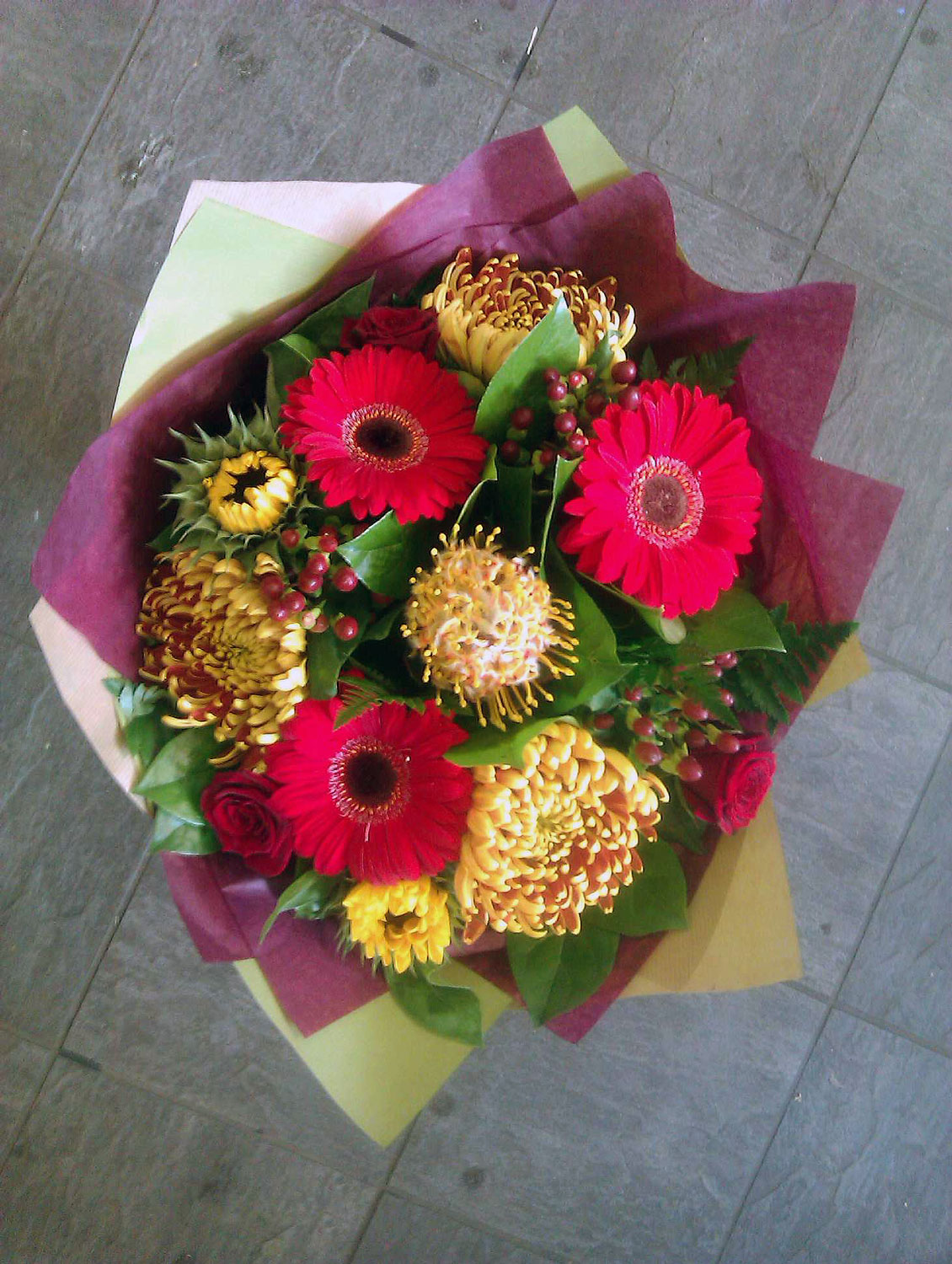 Aegeus---Red-gerbera,-Yellow-leucospernum,-yellow-sunflower,-bronze-blooms,-red-hypericum,-red-roses-accompanied-by-salal-and-fern.-£25-£35-£45.jpg