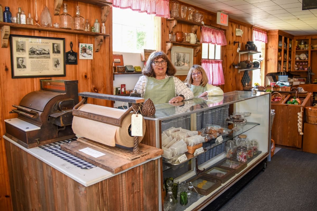 Building Steward Linda Lunt and Society Member Haley Pal selling baked goods at the checkout counter.