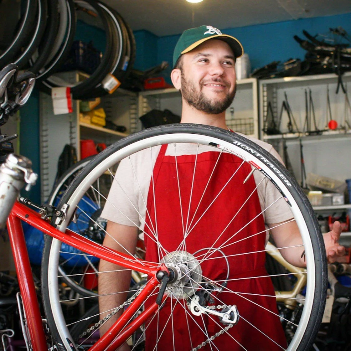 Hector J. Gonzalez holding a bicycle wheel at Biketopia Community Workshop in Berkeley