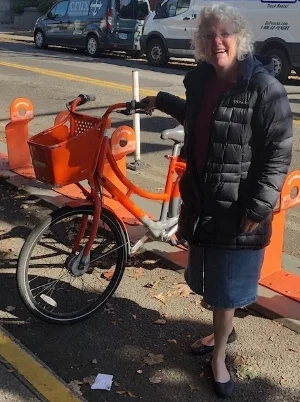 Photo of Kaaren Londahl standing next to an orange biketown bicycle in northeast Portland.